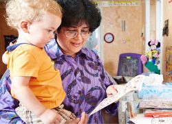 home child care program caregiver reading with child